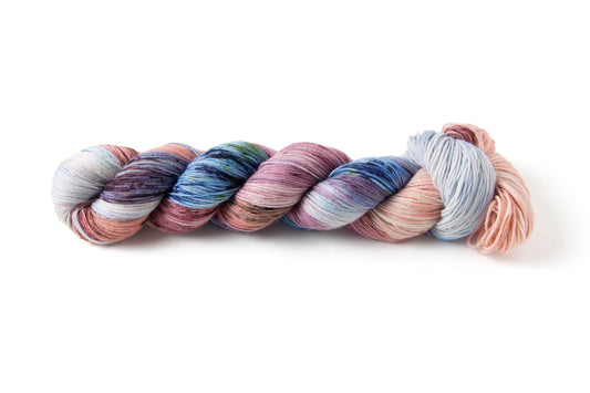 A skein of variegated yarn in pink, blue, and purple, with splashes of other colors speckled on.