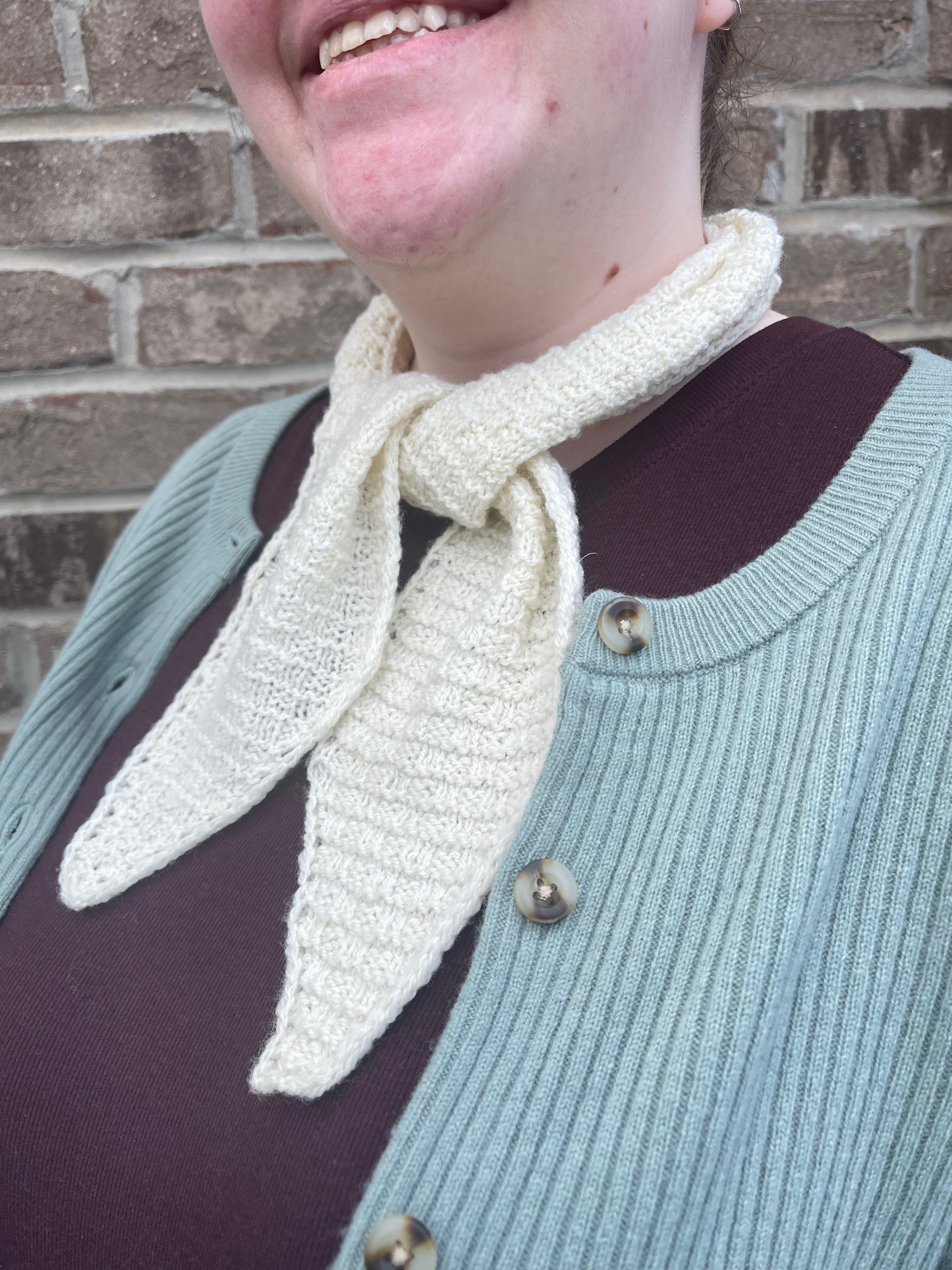 Cat, a smiling white woman, wears a skinny white scarf with an allover square texture.