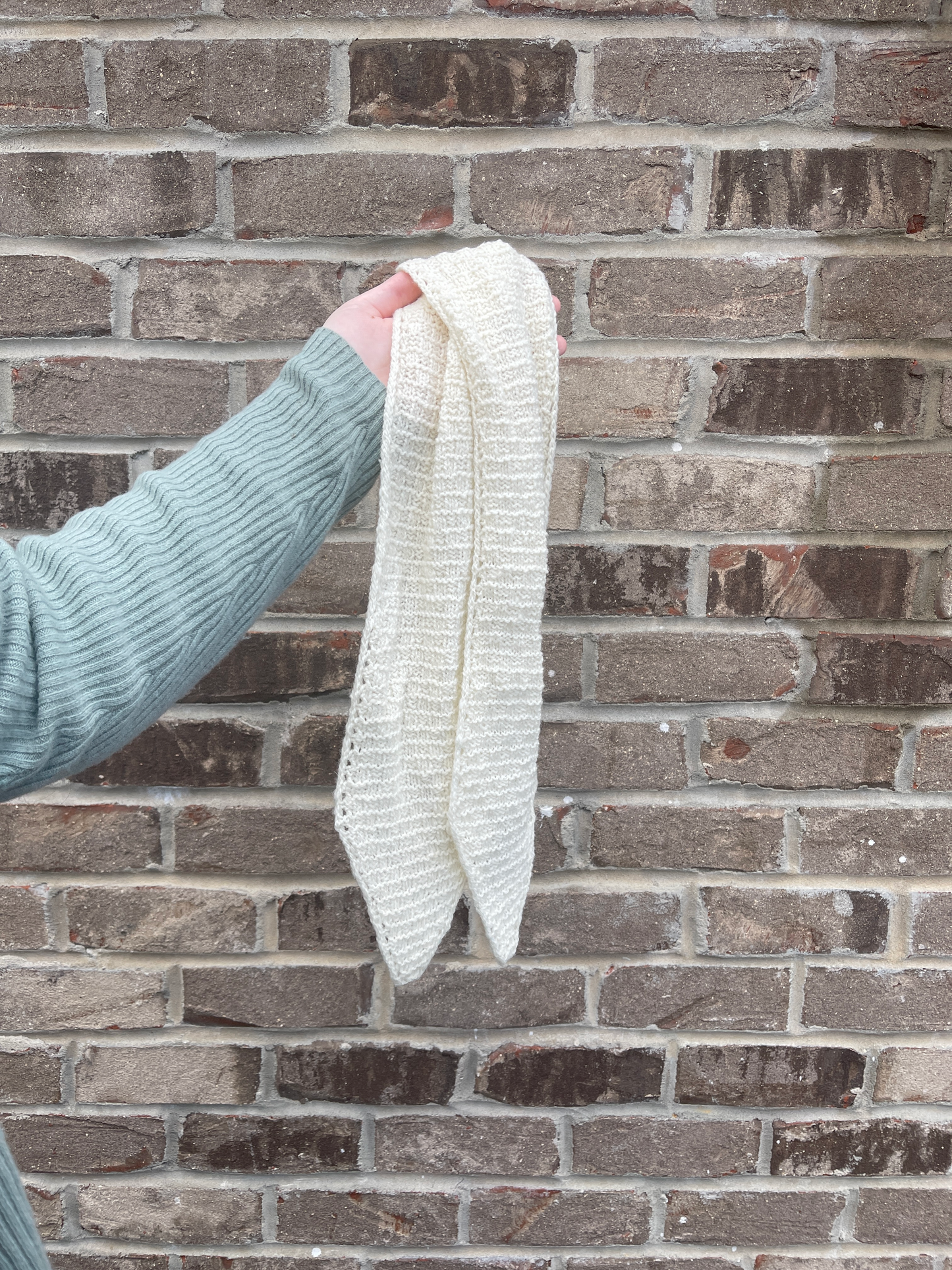 Cat holds the 40-inch scarf against a beige brick wall.