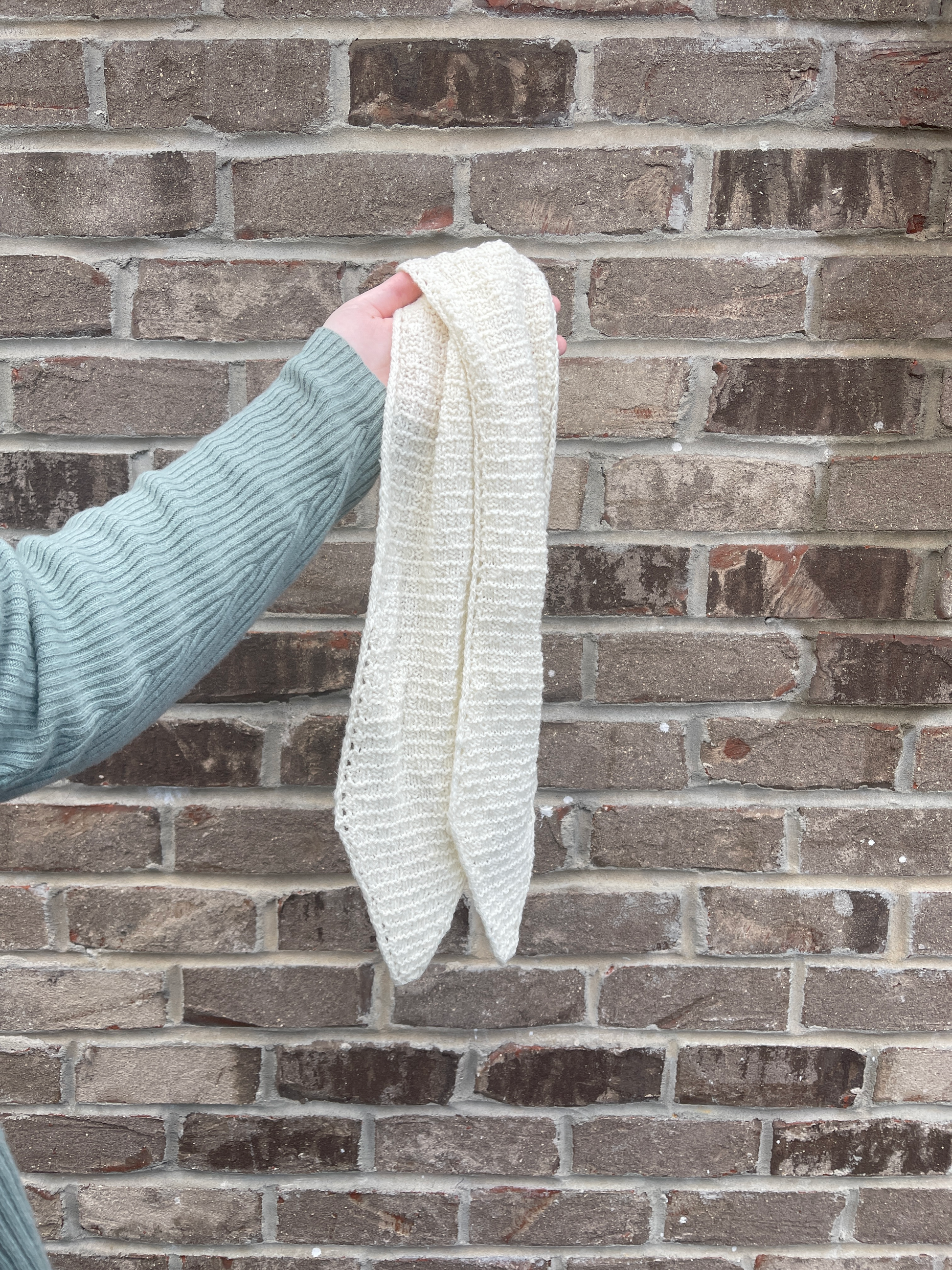 Cat holds the 40-inch scarf against a beige brick wall.