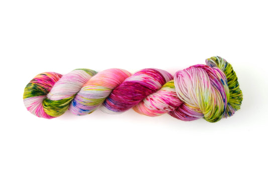 A skein of pink, purple, green, and blue yarn on a white background.