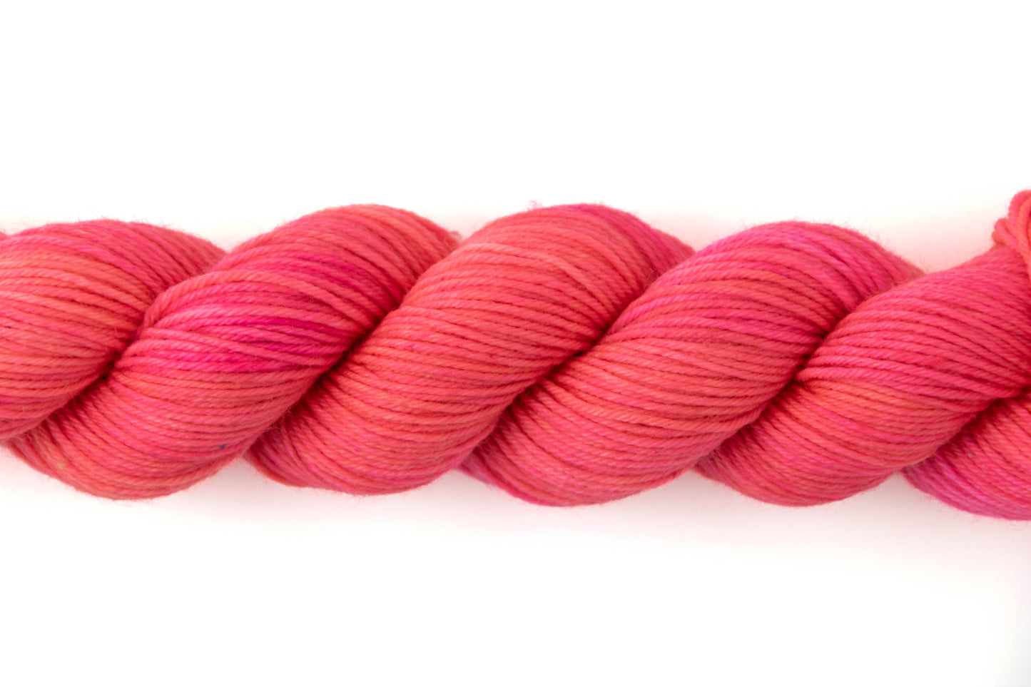 Close view of the yarn, showing off the tonality of the yarn, which ranges from neon pink to coral.