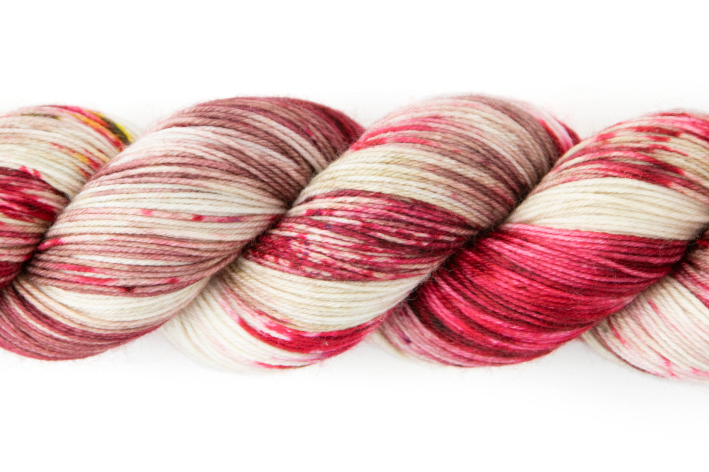 Closeup on the different sections of bright red, dusty mauve, and creamy white, with a few pieces of bright yellow and some black speckling.