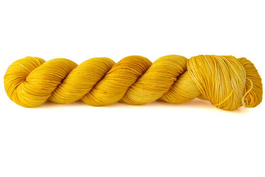 A skein of glowy tonal yellow hand-dyed wool yarn.