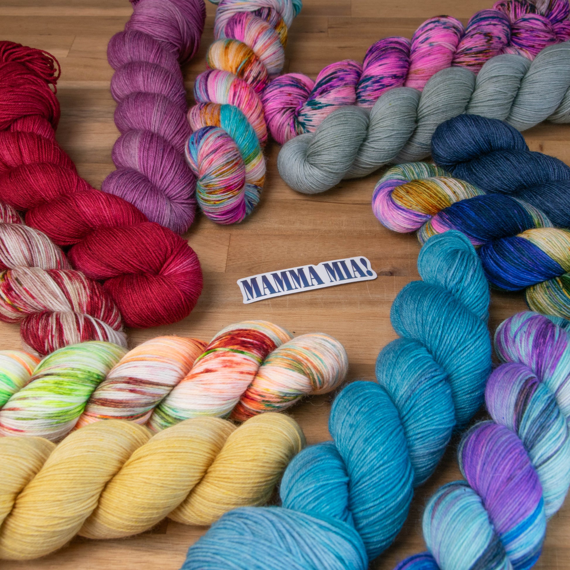 Twelve skeins of yarn around a sticker that says Mamma Mia!