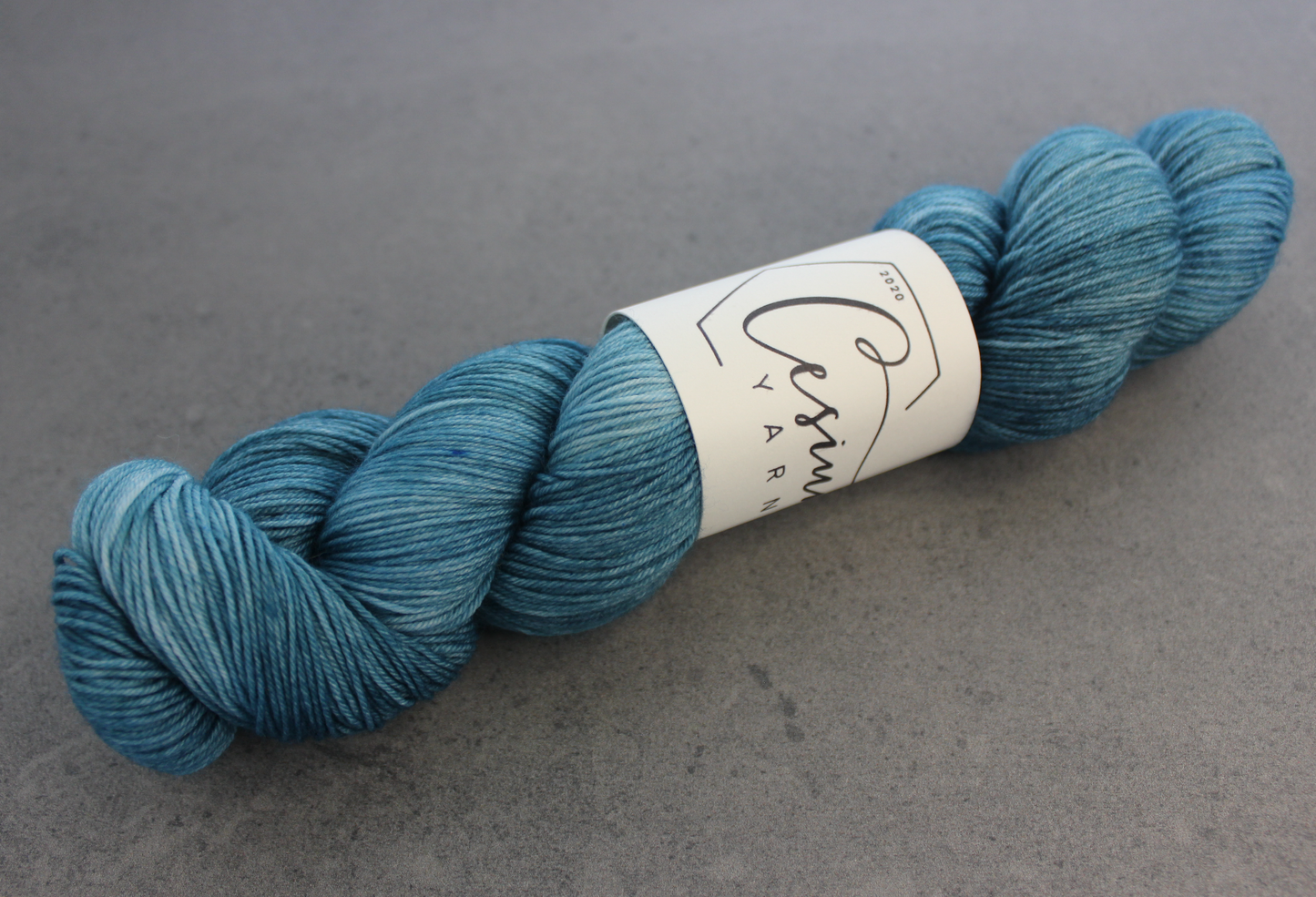 A skein of deep aqua-blue hand-dyed wool yarn.