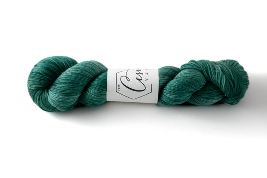 A green tonal hand-dyed wool yarn with blue undertones.
