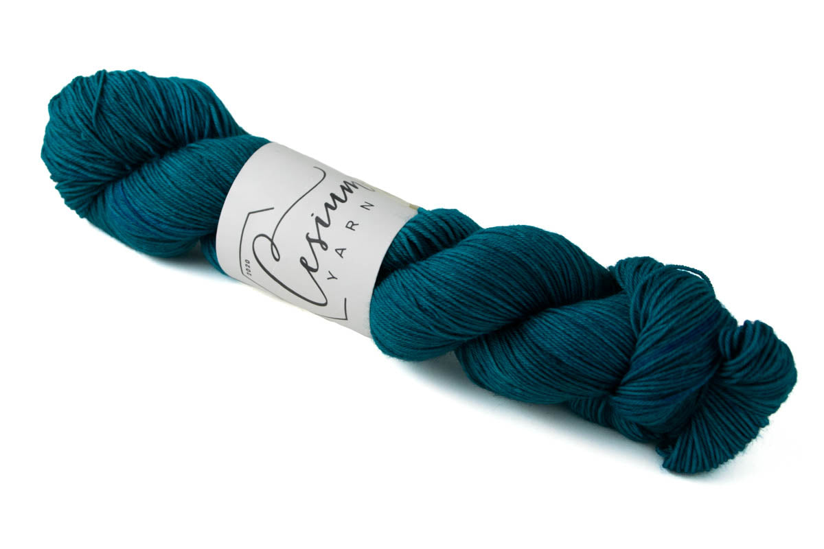 A skein of tonal teal hand-dyed wool yarn.