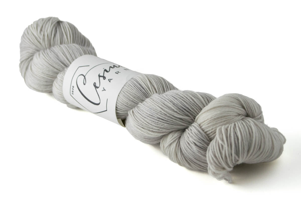 A light gray skein of hand-dyed wool yarn.