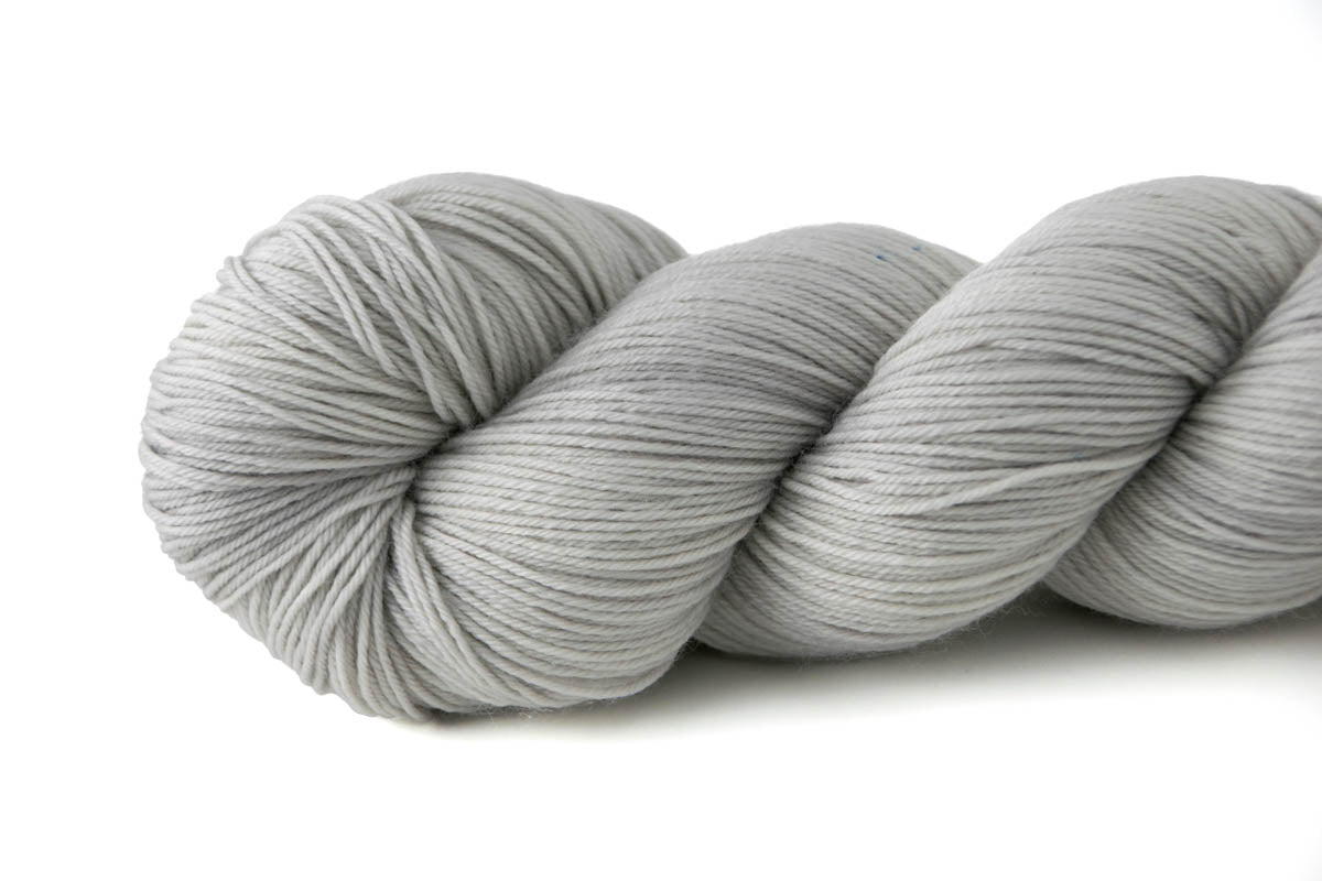 A light gray skein of hand-dyed wool yarn.