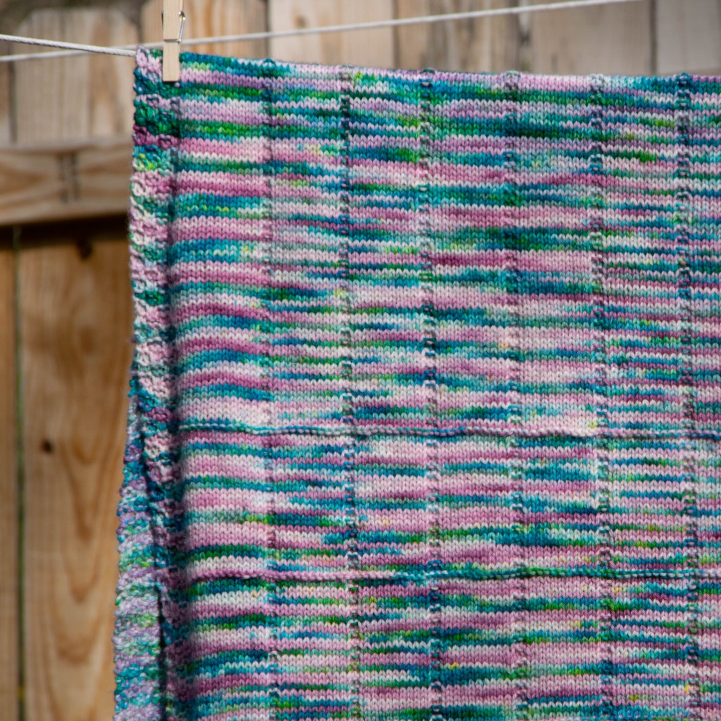 A closeup of the texture of the blanket, consisting of stockinette squares and rectangles and a seed stitch border.