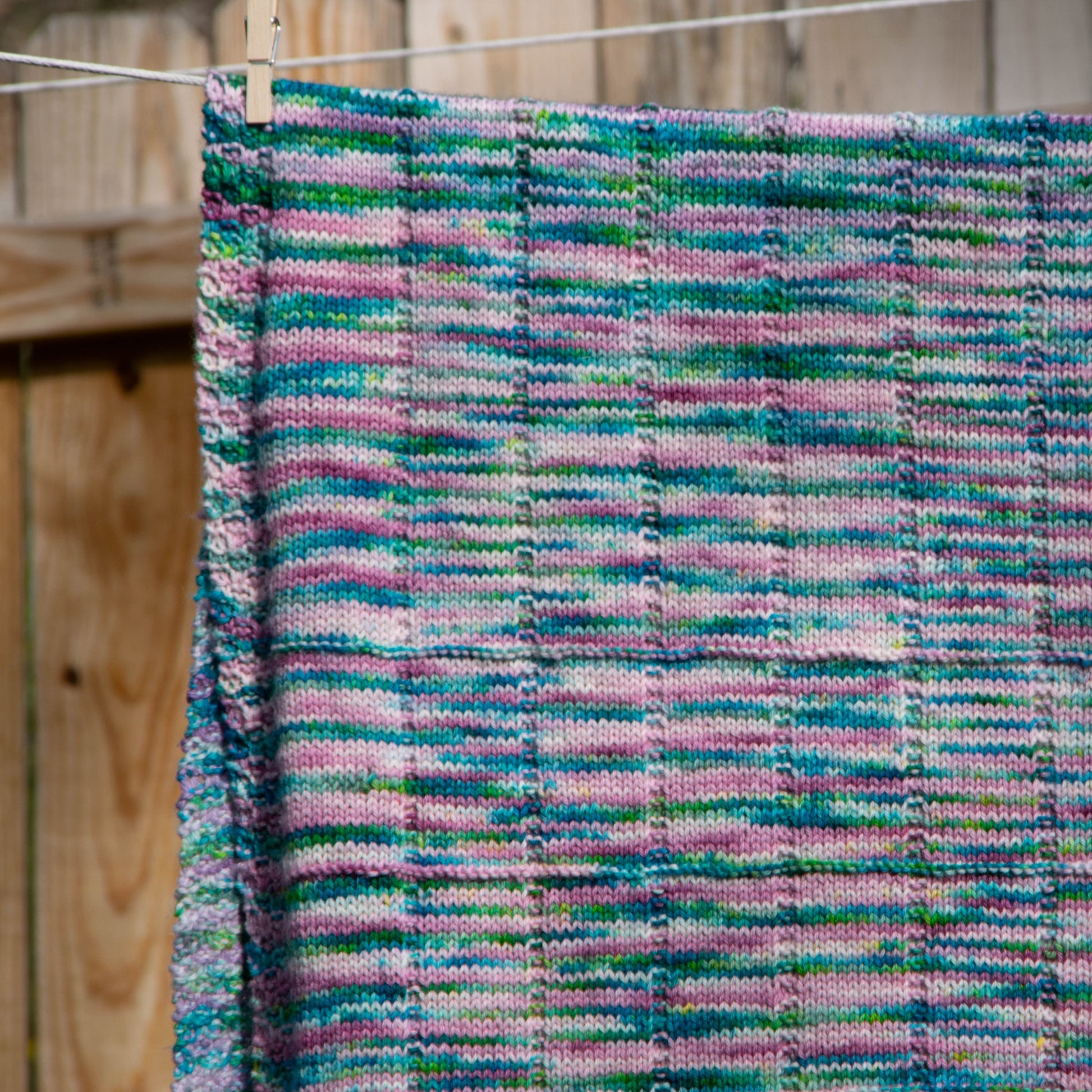 A closeup of the texture of the blanket, consisting of stockinette squares and rectangles and a seed stitch border.