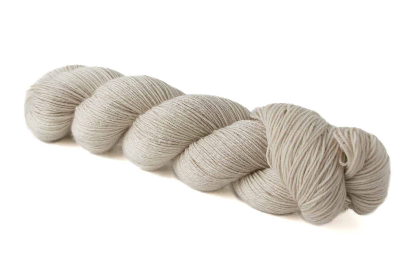 A bone white, cream skein of hand-dyed wool yarn.