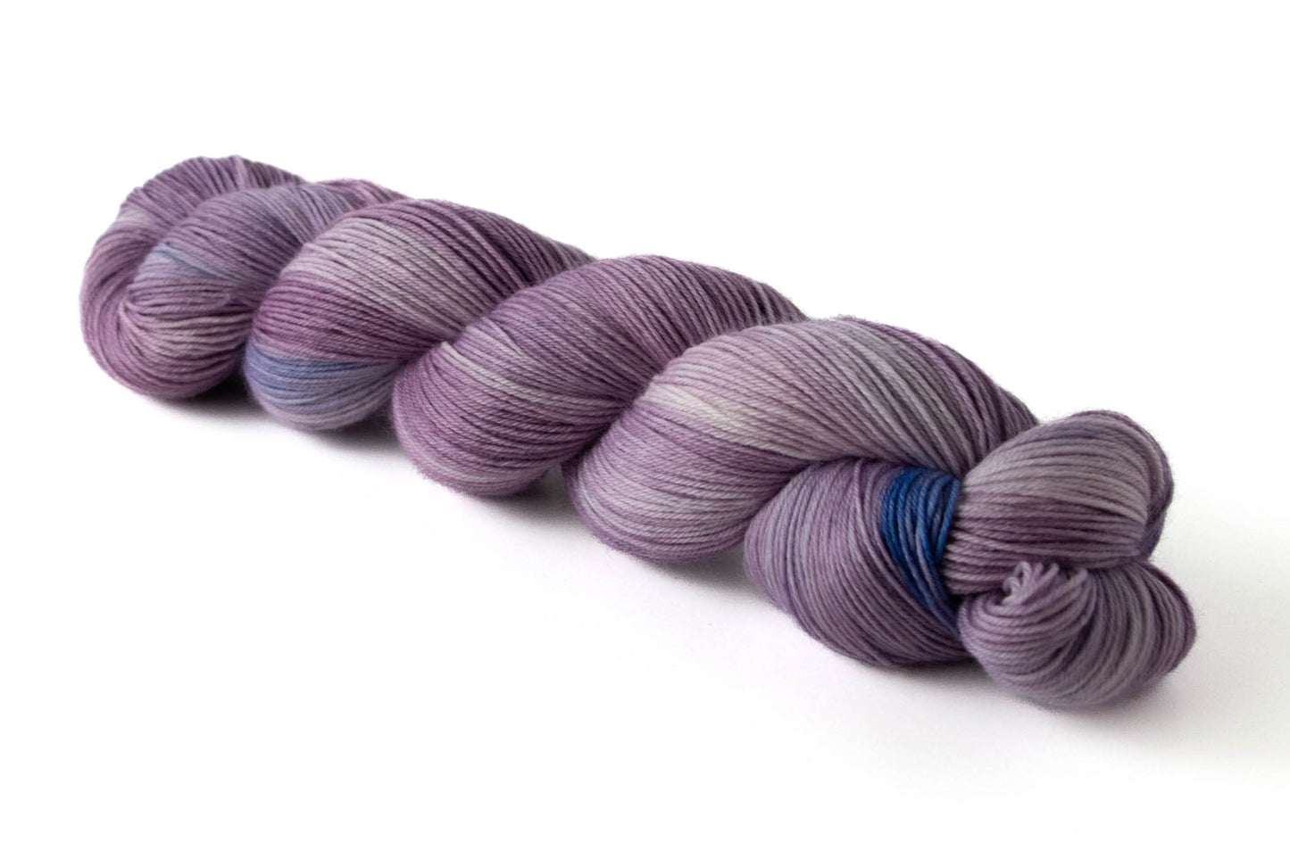 A skein of purple tonal hand-dyed wool yarn with blue highlights.