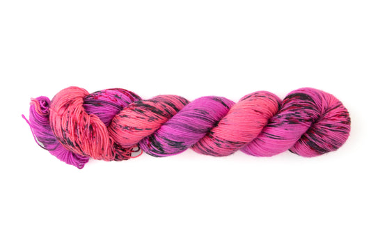 A skein of bubblegum pink and electric purple yarn with black speckles.