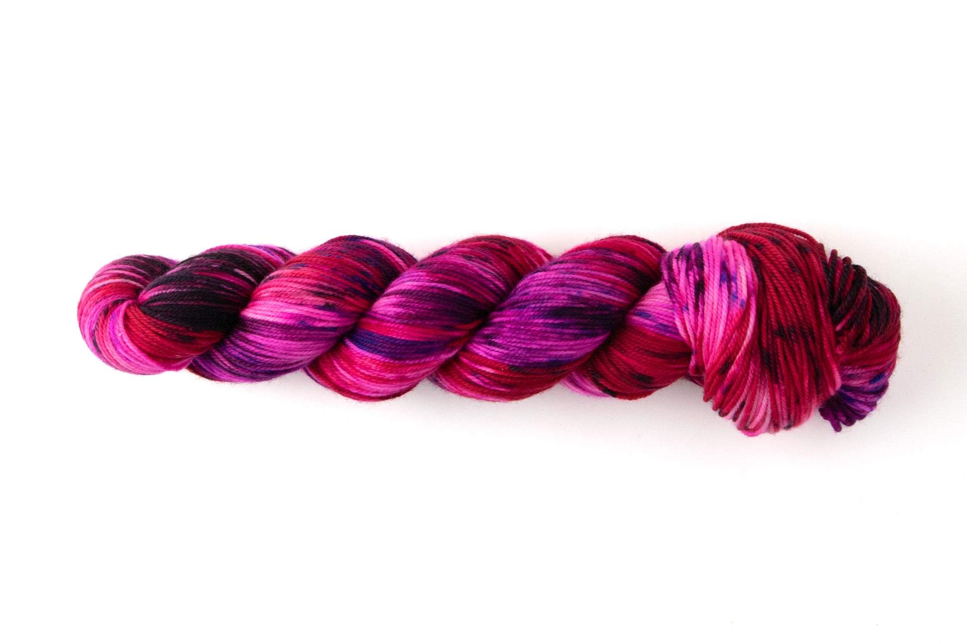 A skein of bright pink and deep purple yarn with sections of red.