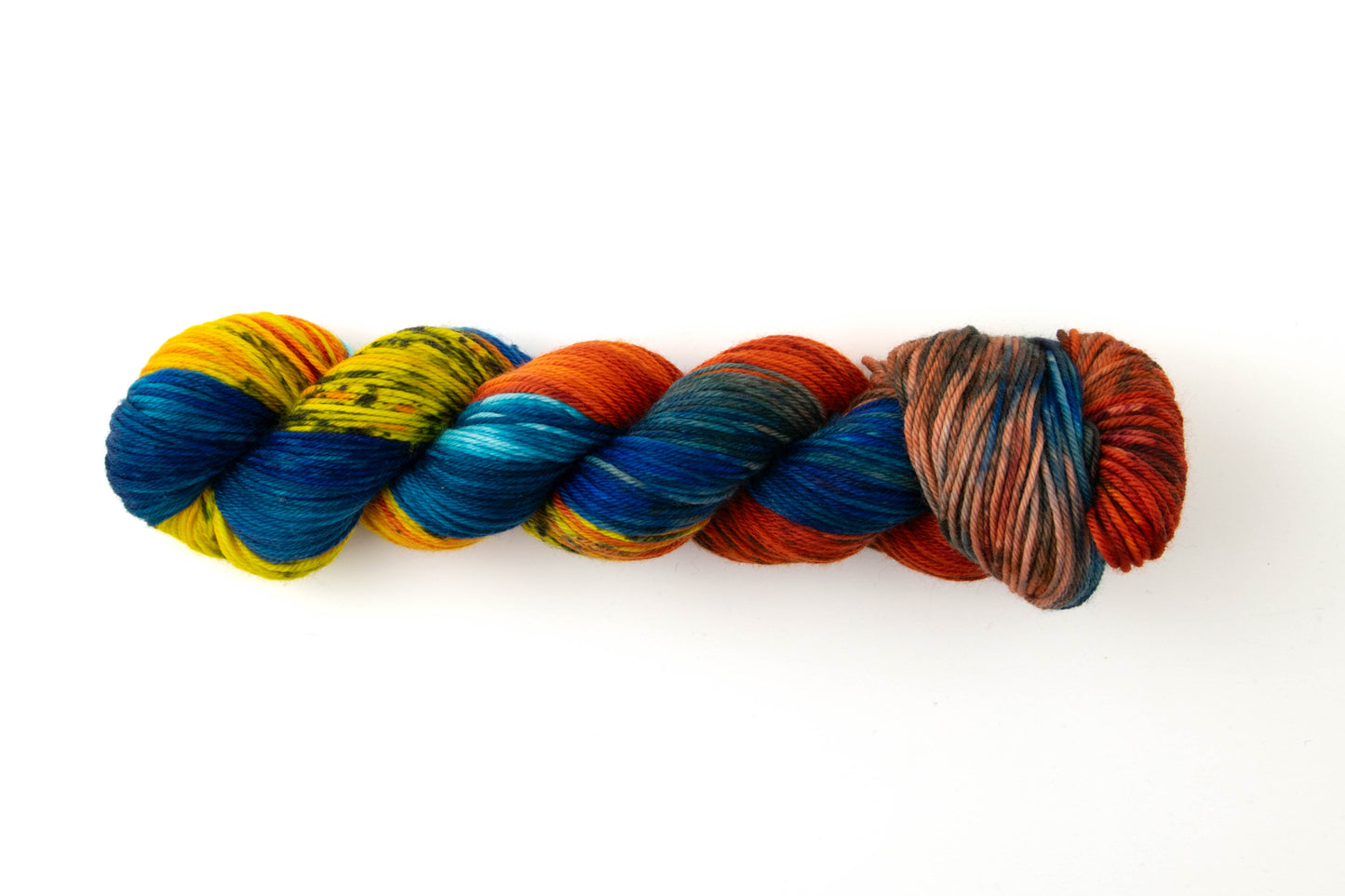 Variegated skein of yarn with red, yellow, blue, and orange sections and black speckles.