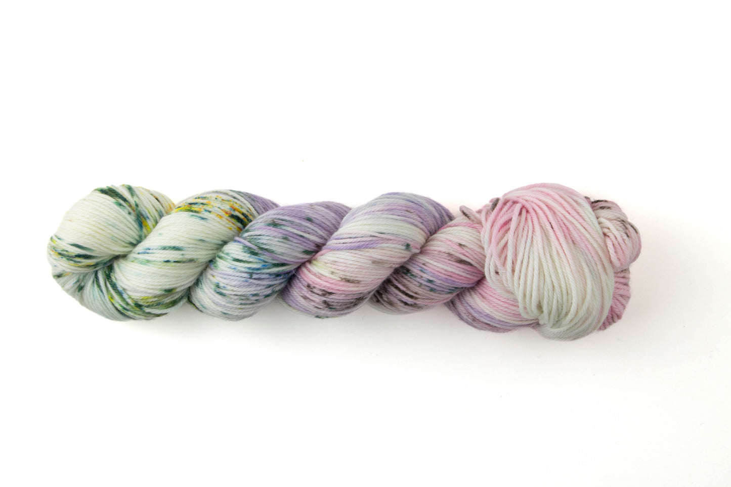 A pastel variegated skein with pink, purple, green, and white sections and green speckles.