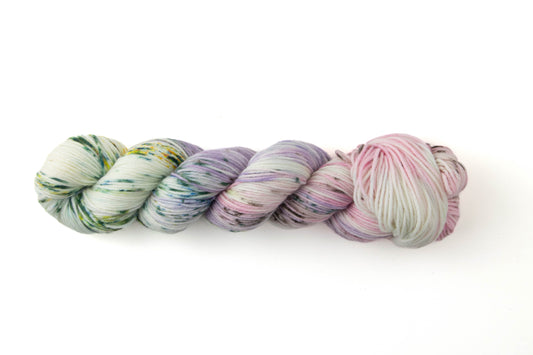 A pastel variegated skein with pink, purple, green, and white sections and green speckles.