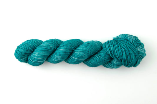A bright teal tonal skein of yarn.