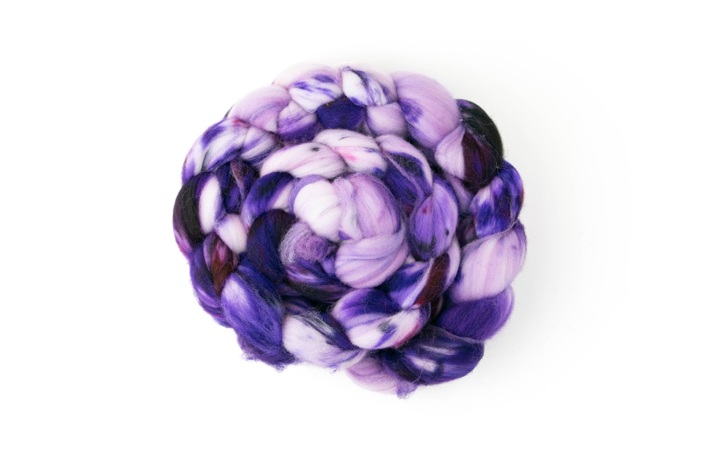 A braid of superwash yarn wrapped into a bun, with sections of almost black, pastel, and mauve-y purple.