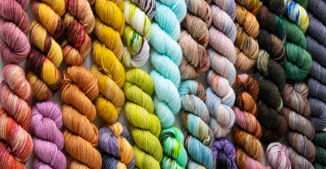 All of the mini skeins from the Cesium Yarn Clue collection laid out next to each other in a rainbow.