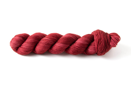A skein of bright red hand-dyed tonal yarn.