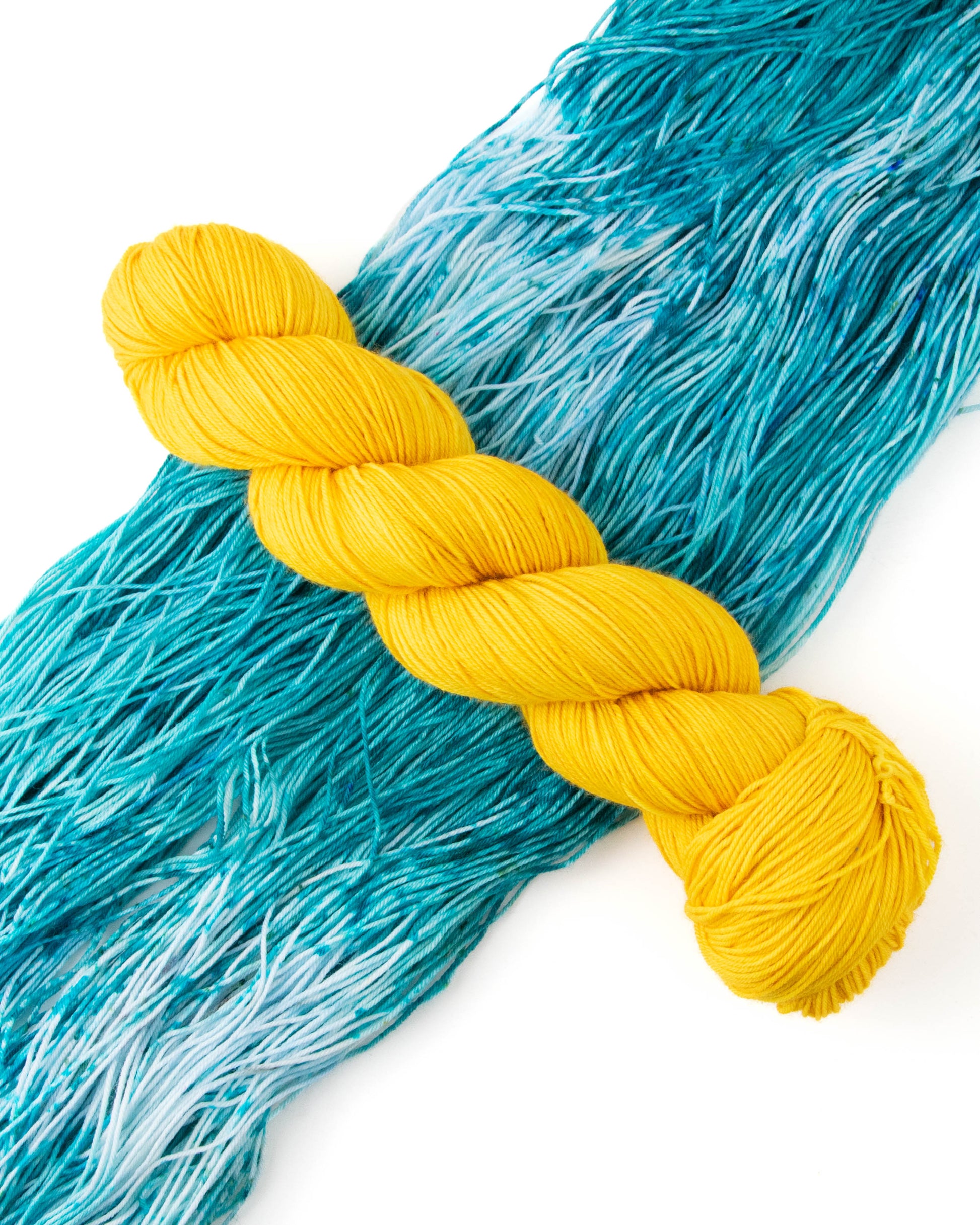 A skein of yellow yarn on top of aqua yarn.