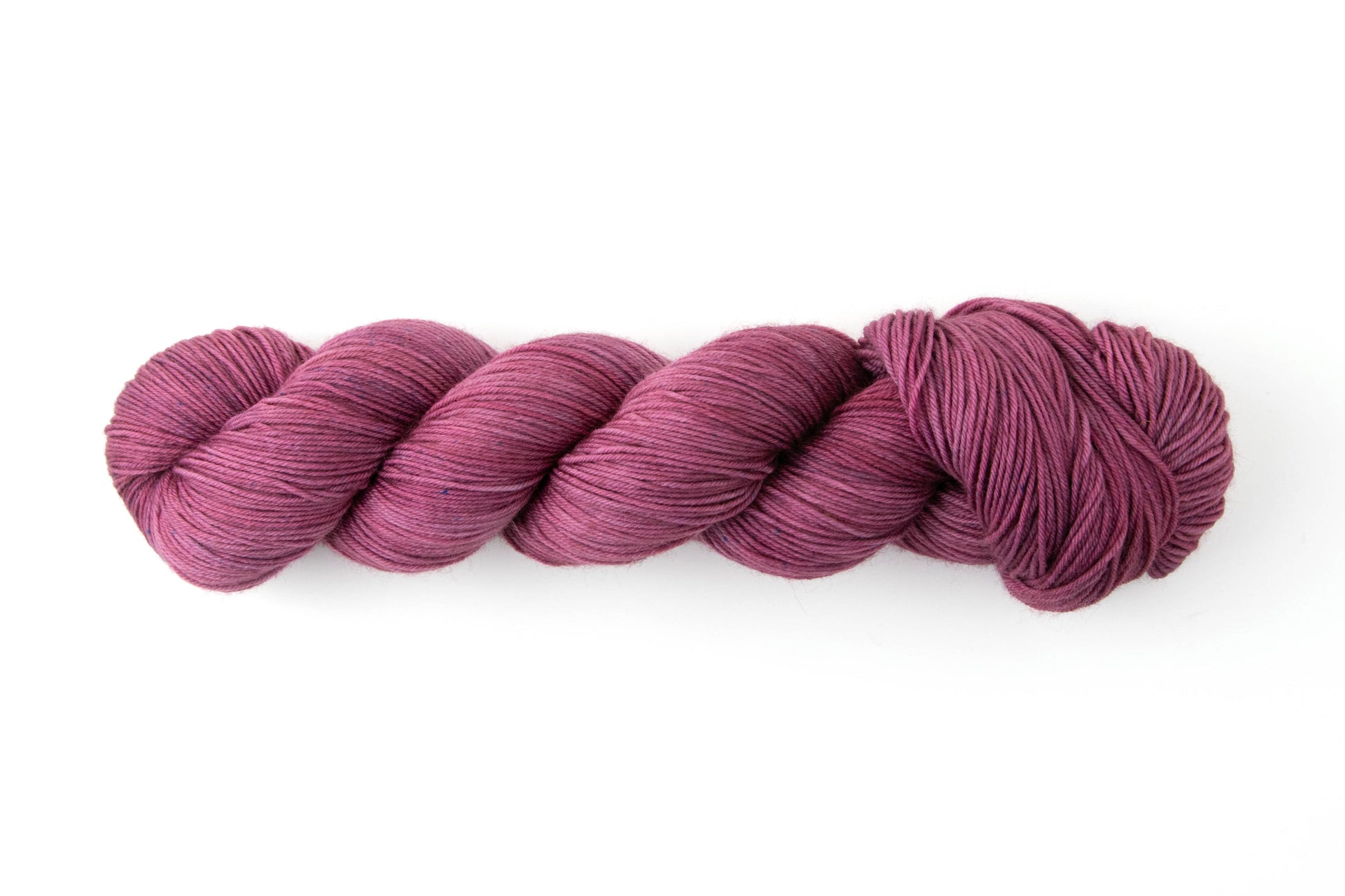 A skein of mauve to purple yarn with the occasional navy speckle.