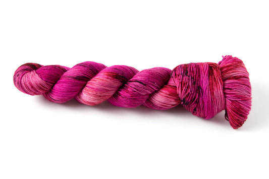 An electric pink skein of hand-dyed yarn, with darker and lighter sections throughout.