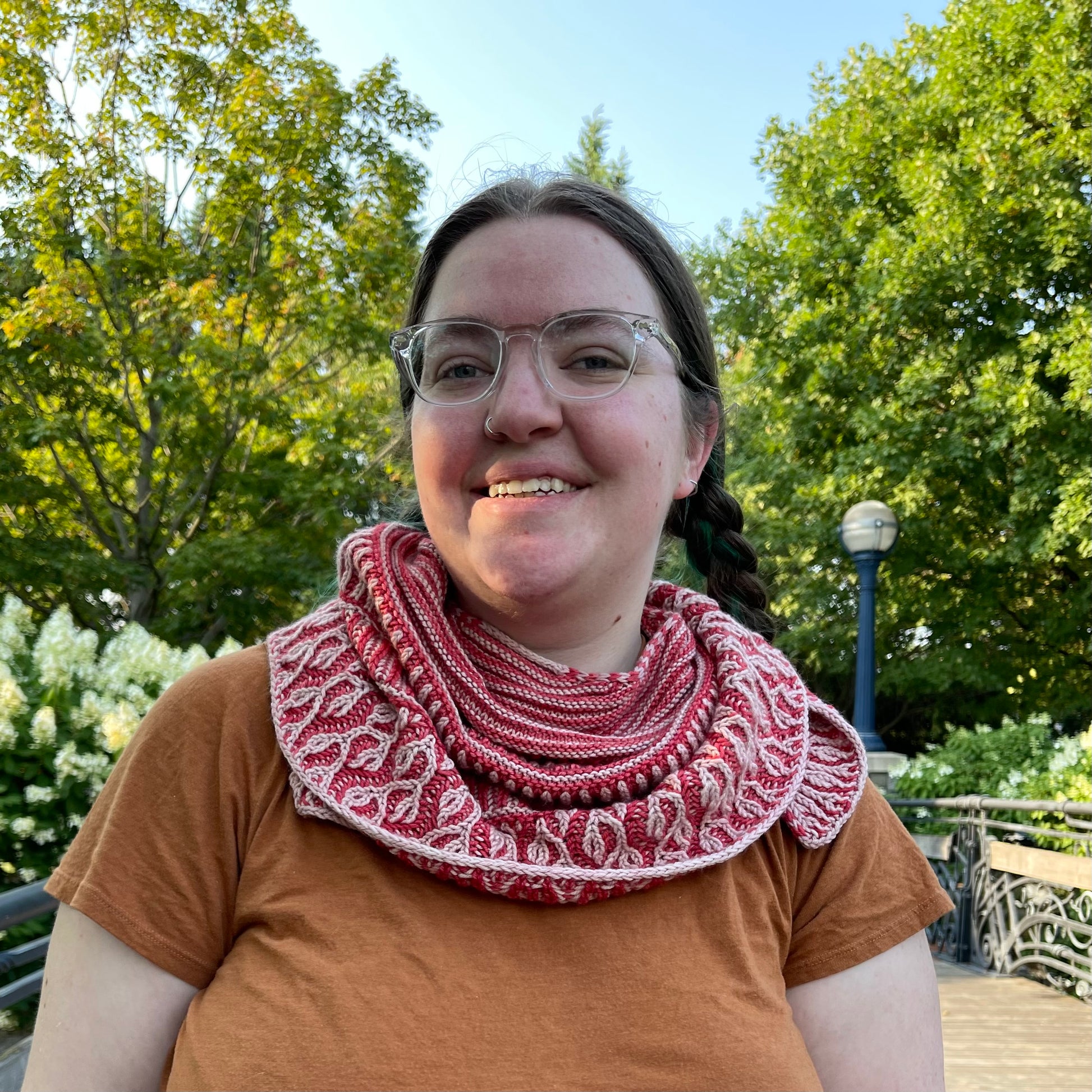 Cat, a white woman, wears the Gradual Brioche shawl wrapped around her neck.