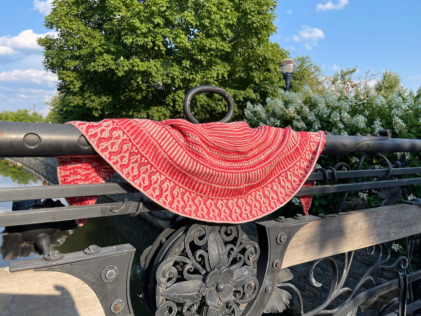 A red and pink shawl hanging on an iron bridge railing.