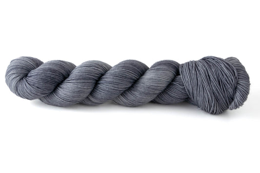 A skein of light gray hand-dyed wool yarn.