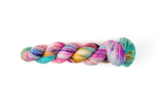 A bright skein of yarn with a subtle white background and cheerful sections of pink, aqua, orange, purple, and blue.