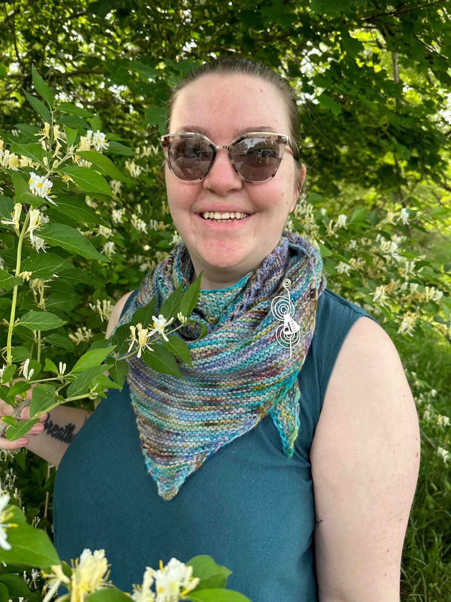 Cat, a white woman, wears a textured knit shawl in a blue and green yarn.