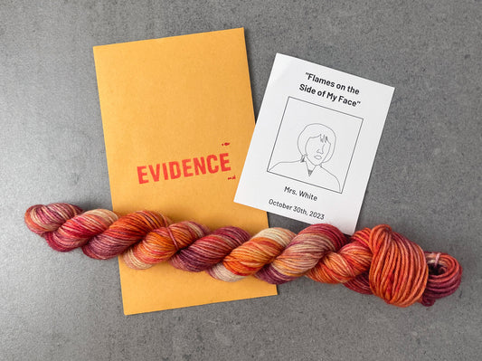 A skein of red, orange, yellow, and pink variegated yarn on top of an envelope stamped with "Evidence" and a card with a drawing of Mrs. White on it.