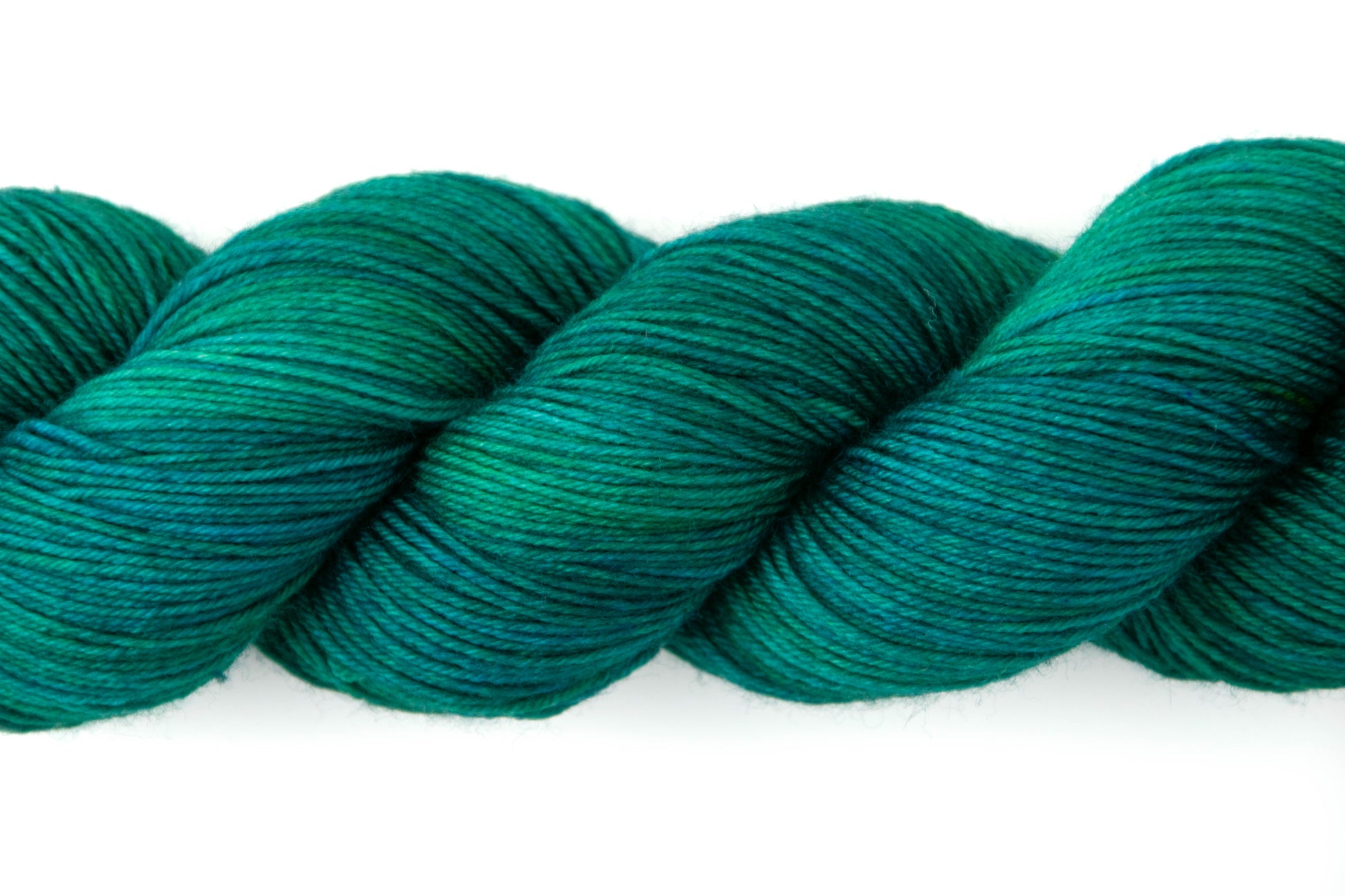 Close view of the texture of the yarn, which has almost navy sections and almost grass green sections that result in a teal effect.