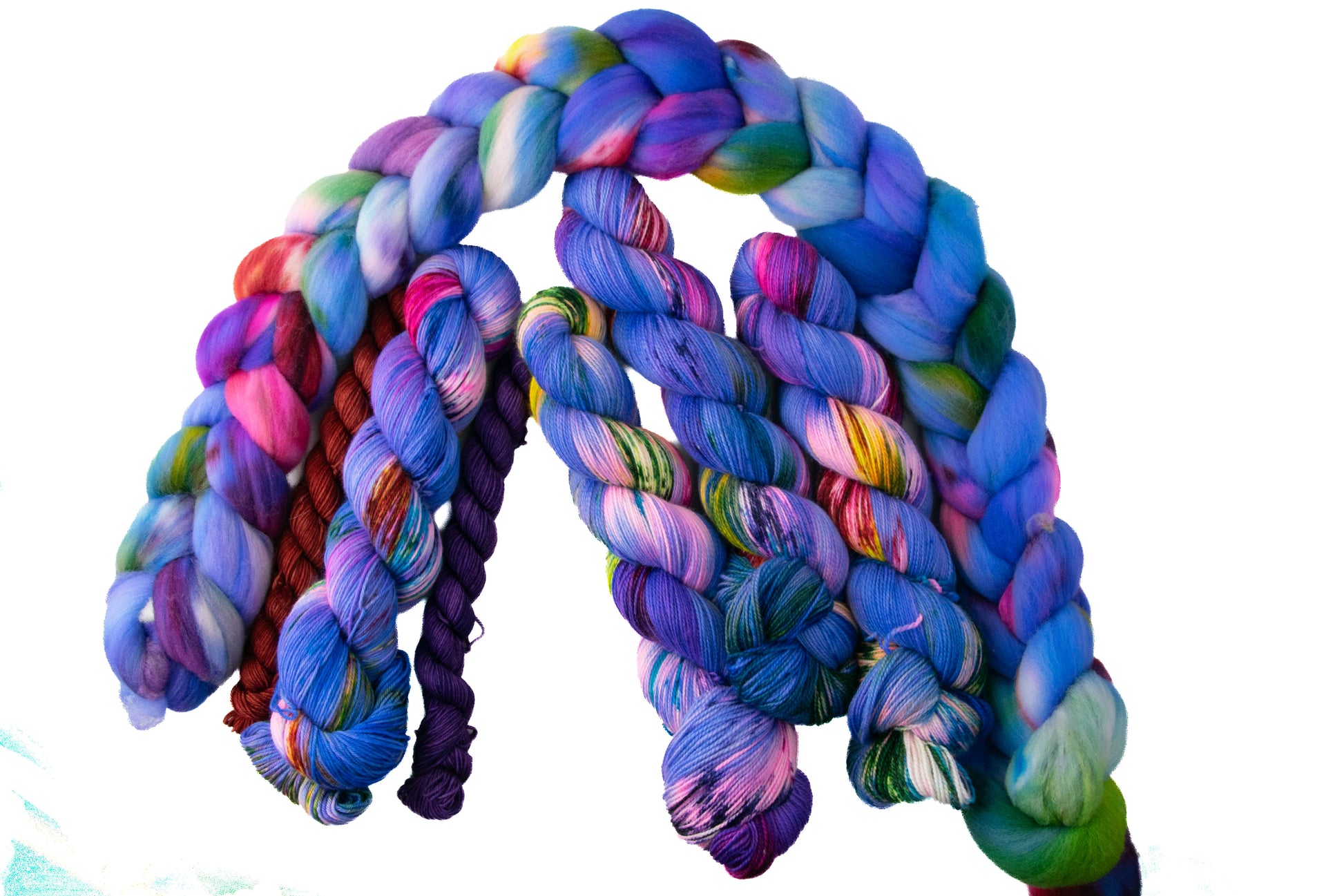 Skeins of brightly colored yarn flanked by a red and a purple mini skein and surrounded by spinning fiber in the same color.