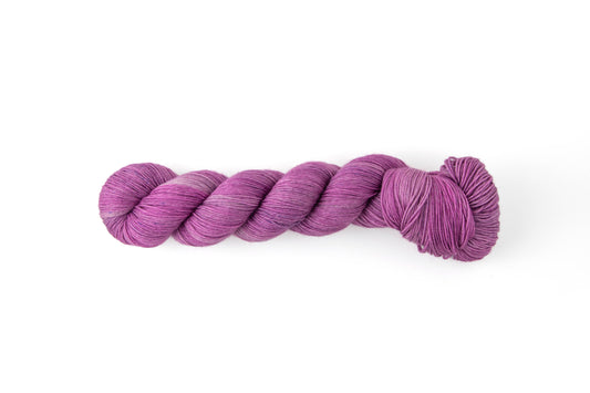A skein of hand-dyed yarn that sits right on the edge between pink and purple.