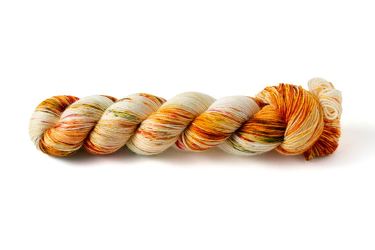 A skein of variegated yarn with swathes of red and orange, olive green speckles, and  strands of brown on a white background.