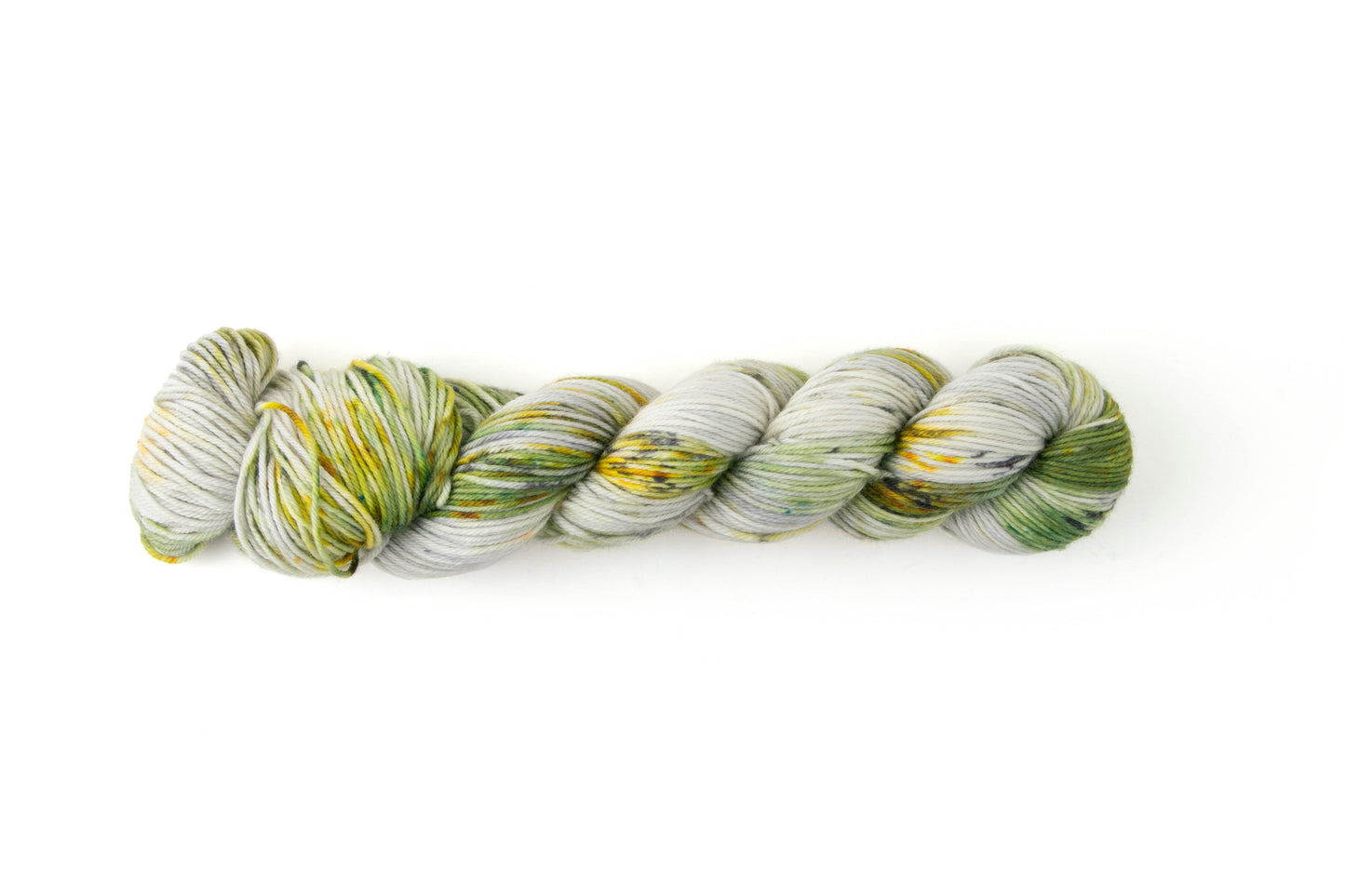 A skein of hand-dyed yarn with a gray background, large swathes of green, and speckles of orange, yellow, and dark gray.