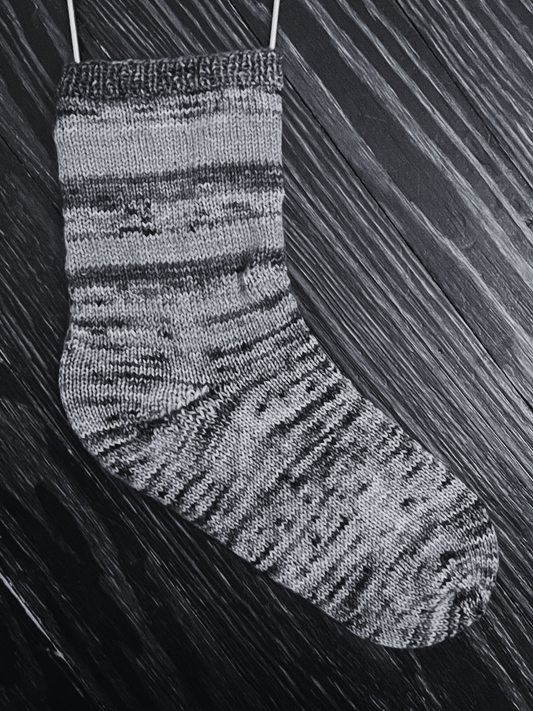 A black-and-white photo of a striped knit sock.