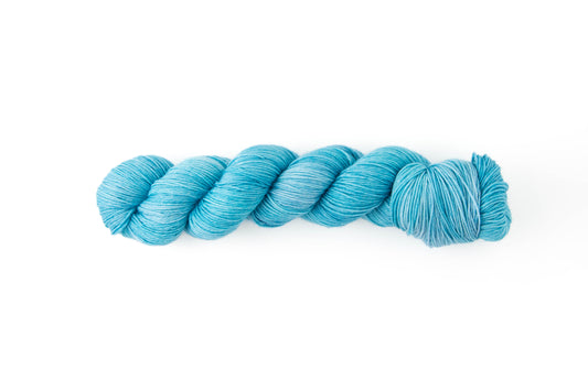 A bright aqua skein of hand-dyed yarn.