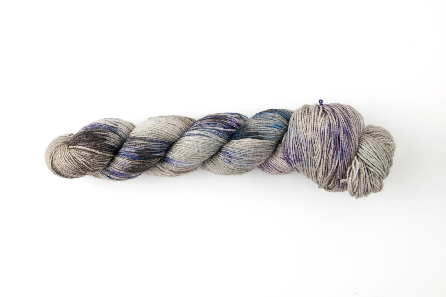 A skein of gray yarn with purple, blue, and dark gray sections.