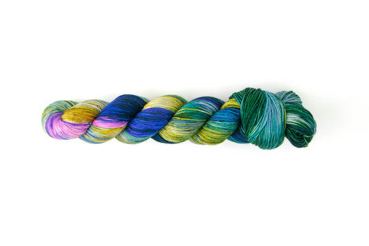 A skein of green, blue, and yellow yarn with a section of neon pink at the top.