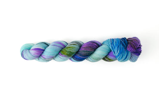 A skein of hand-dyed yarn in blue, navy, green, and purple.