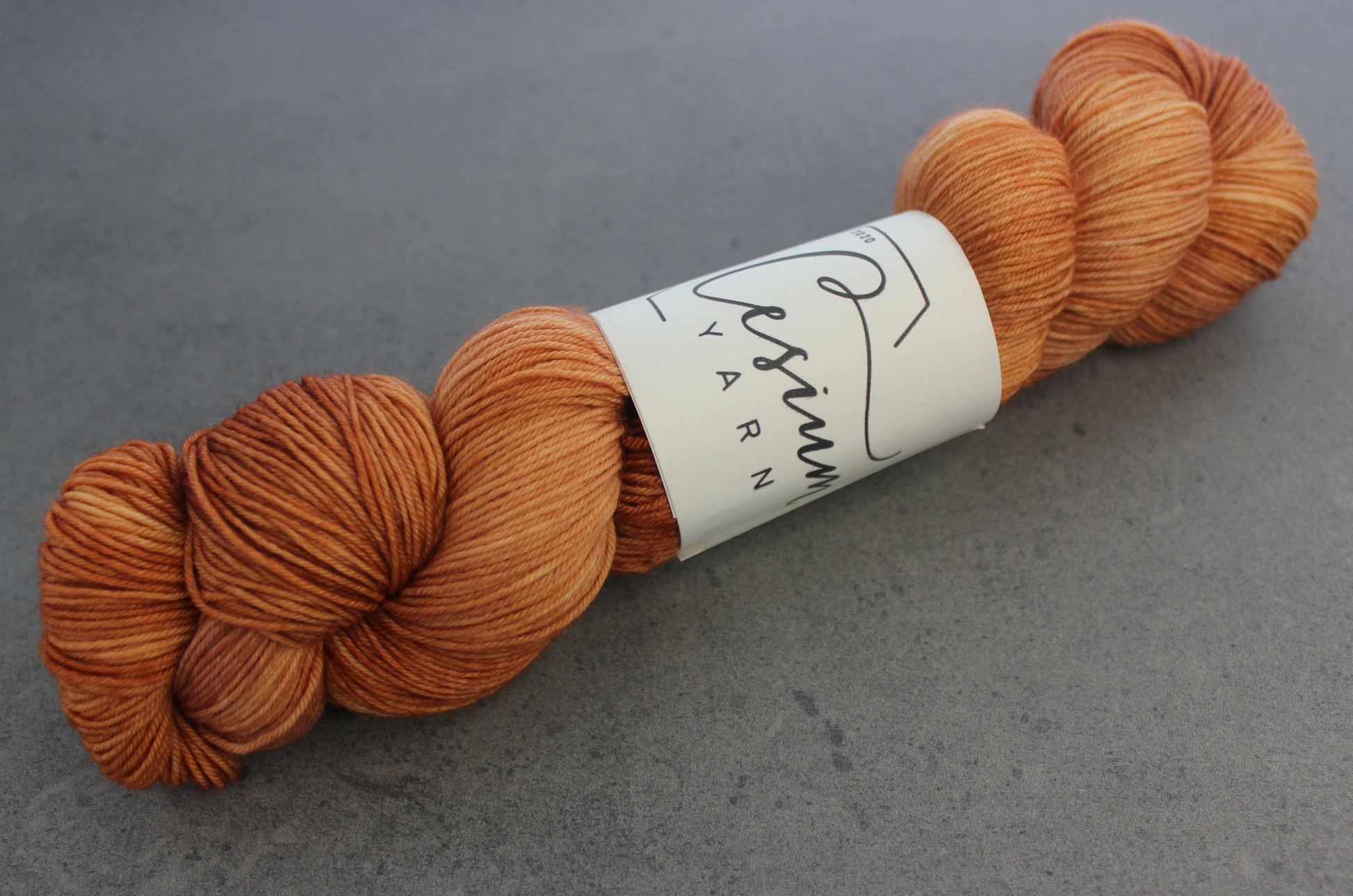 A skein of subdued orange tonal hand-dyed wool yarn.