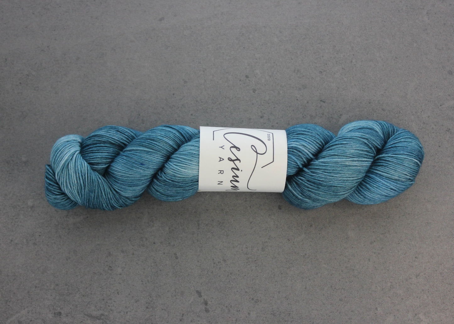 A skein of deep aqua-blue hand-dyed wool yarn.
