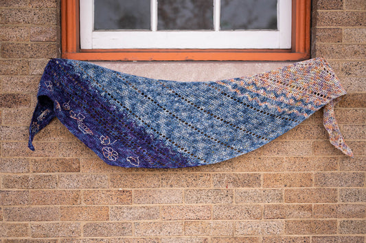 The Replenishment crochet shawl hung on a windowsill.