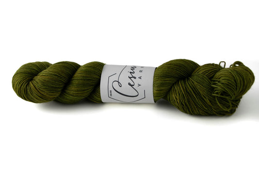 A skein of tonal green hand-dyed wool yarn.